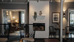 A modern living room with a fireplace, seating area, and a dining table. - Home Hotel Uman (Umea)