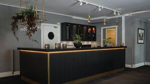 A modern kitchen with a black countertop, gold accents, and pendant lighting. - Home Hotel Uman (Umea)