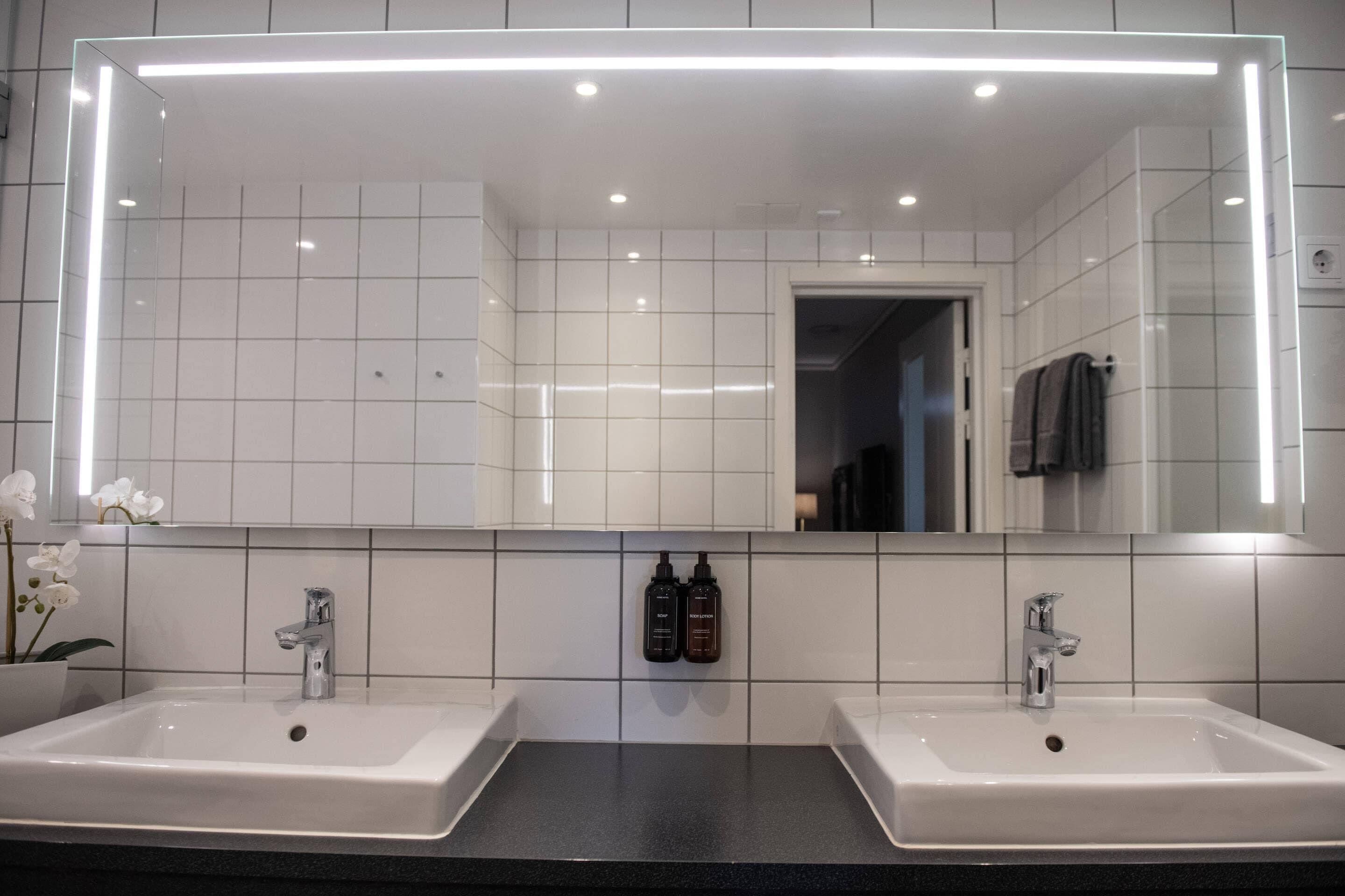 Une salle de bain avec deux lavabos, un grand miroir et une orchidée en pot.