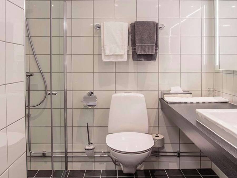 A modern bathroom with a glass shower enclosure, a toilet, a sink, and two towels.