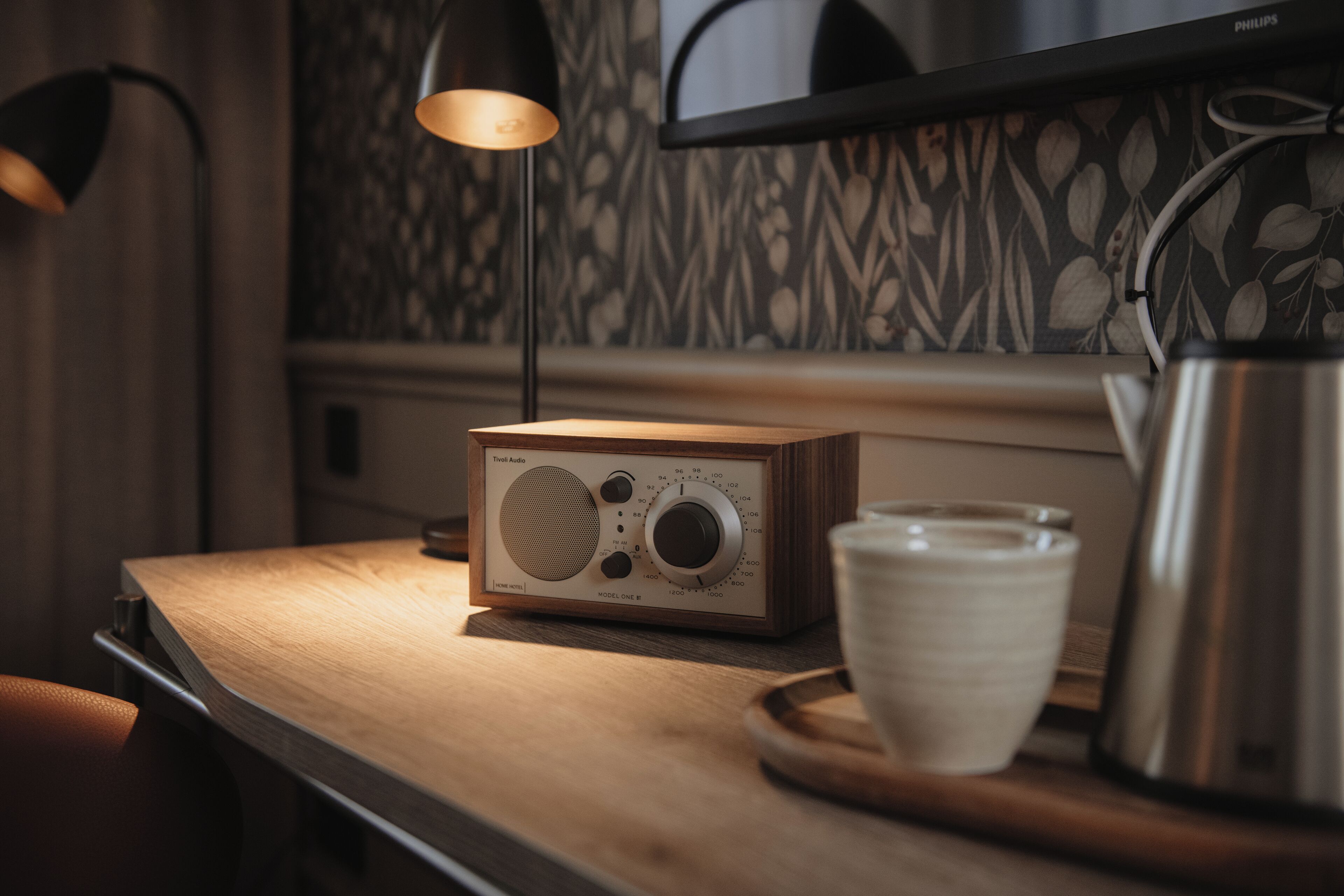 A wooden table with a vintage radio, a cup, and a kettle.