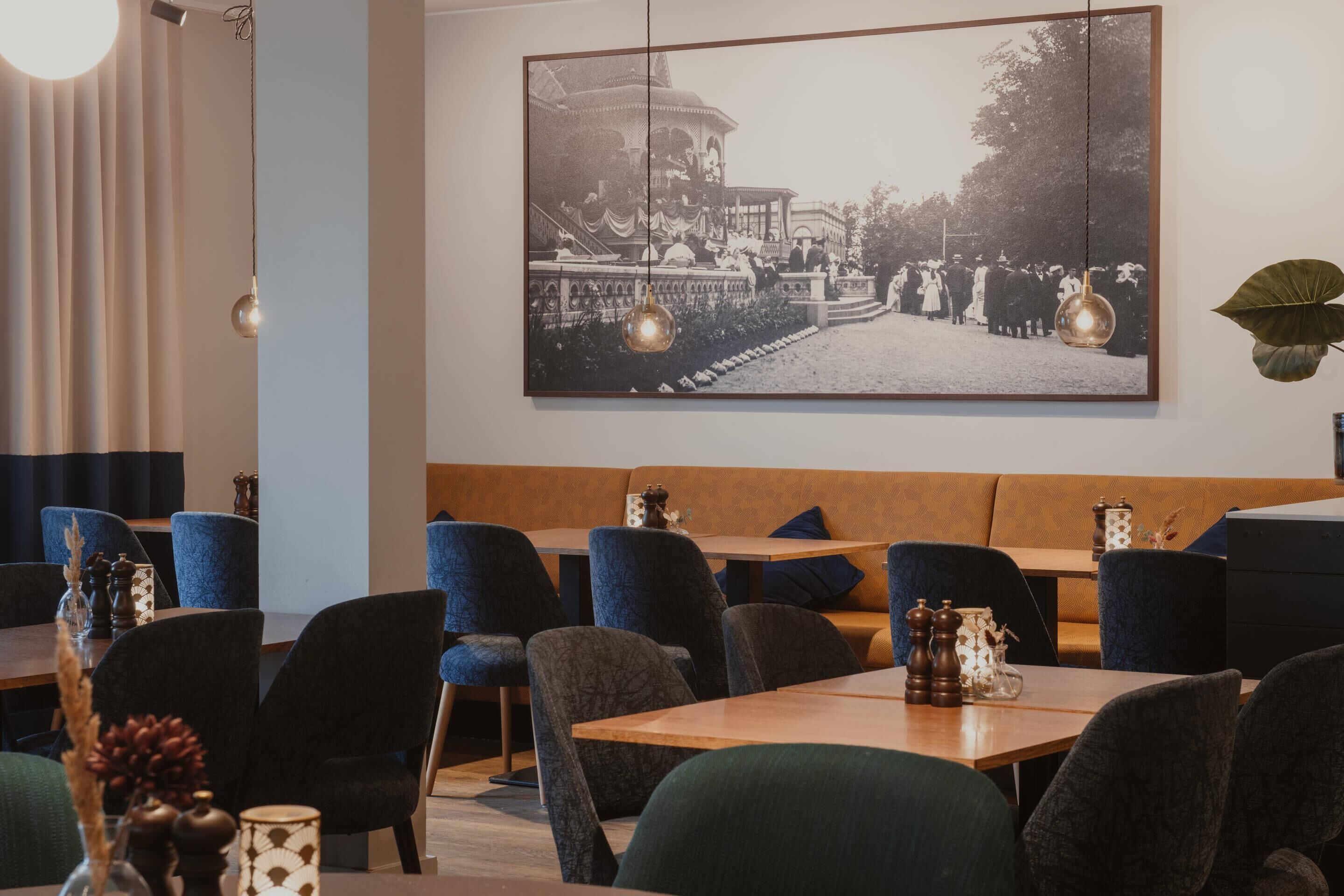 Un restaurante con una larga mesa y sillas, un banco y una fotografía grande en el marco en la pared.