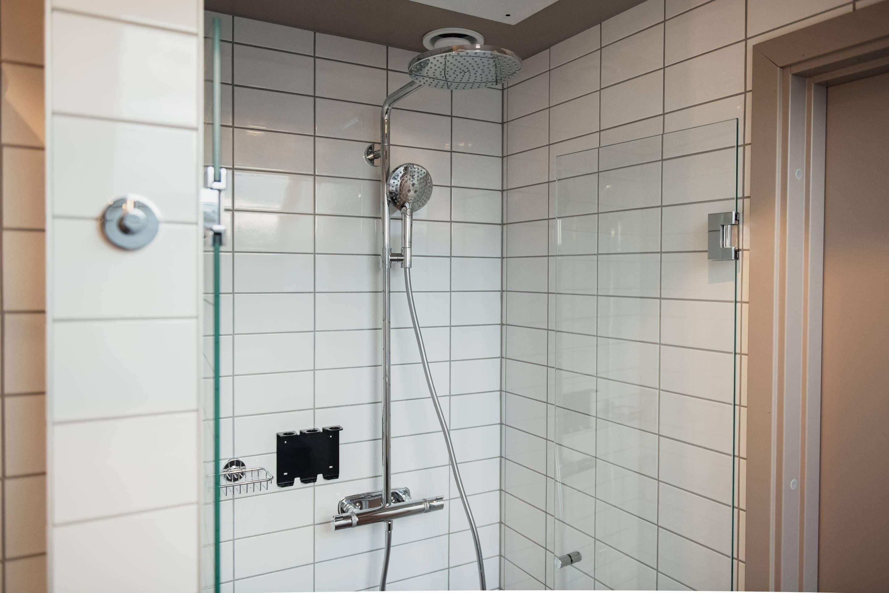 A modern shower with a glass enclosure, chrome fixtures, and a tiled wall.