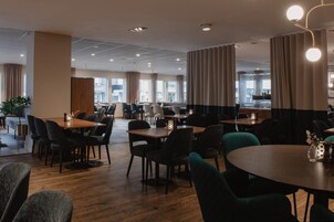 Un restaurante espacioso con numerosas mesas y sillas, ventanas amplias y una decoración de diseño moderno.