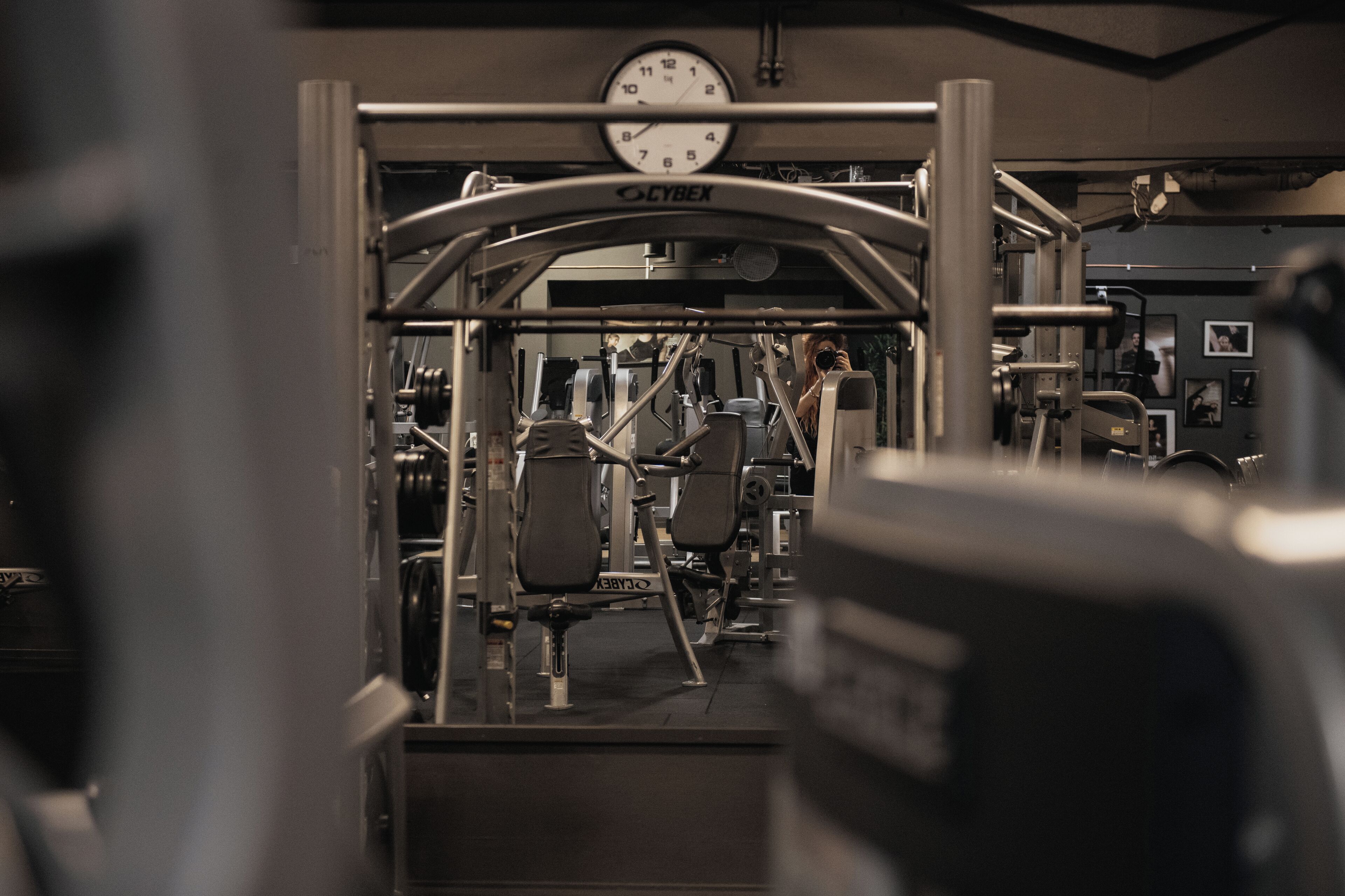 A gym with various exercise equipment, a clock above the entrance, and a Cybex logo.