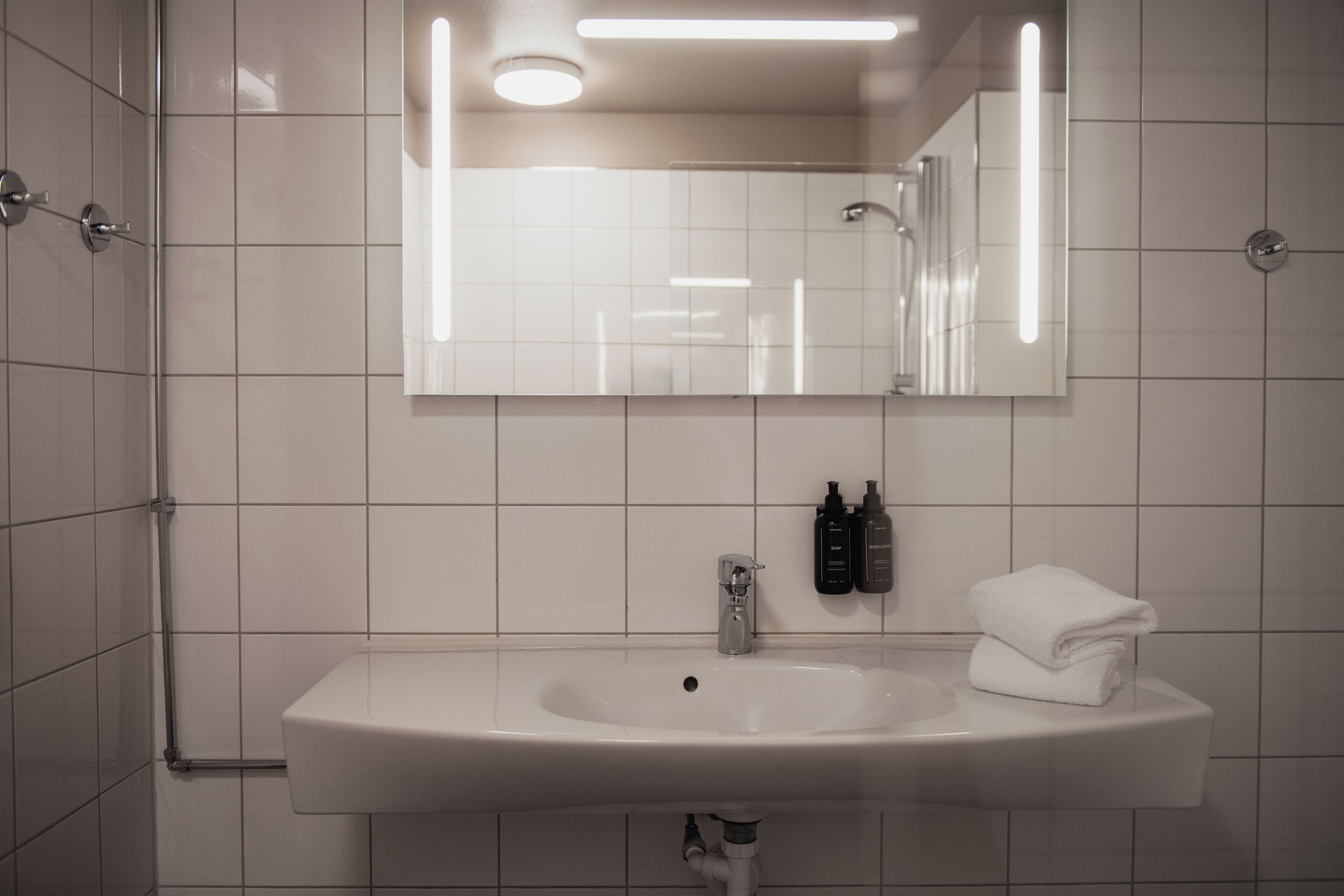 Un baño con un lavamanos blanco, un espejo y una toalla.