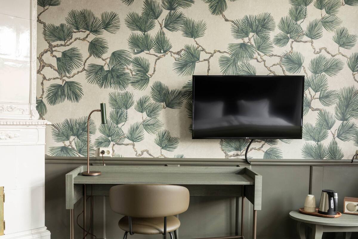 Una habitación con un escritorio, una silla y un televisor fijado a la pared.