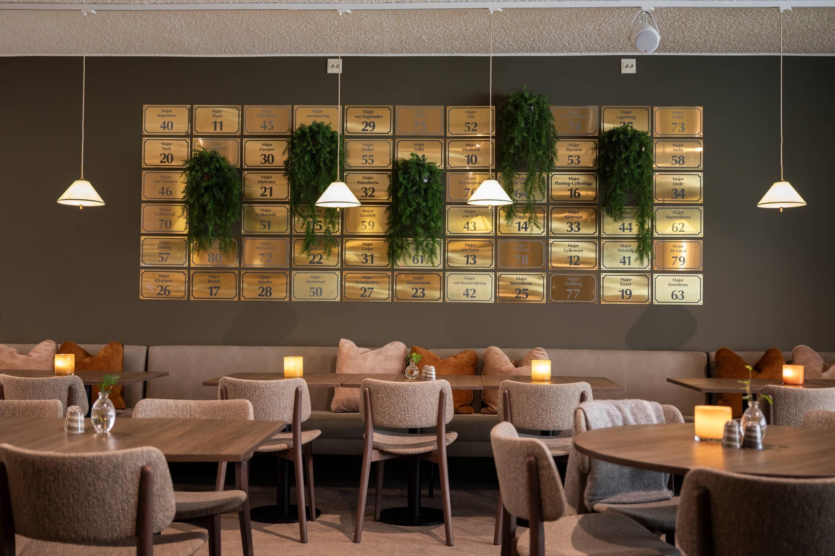 Un restaurante con una pared de placas numeradas, asientos acolchados e iluminación colgante.