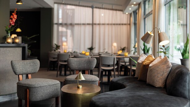 A modern interior with a sofa, chairs, and a round table.
