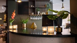 A modern bar area with a curved counter, candles, and potted plants.