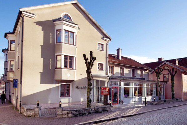 Classic hotel building with a corner entrance and glass facade, set amidst a charming cobblestone street.