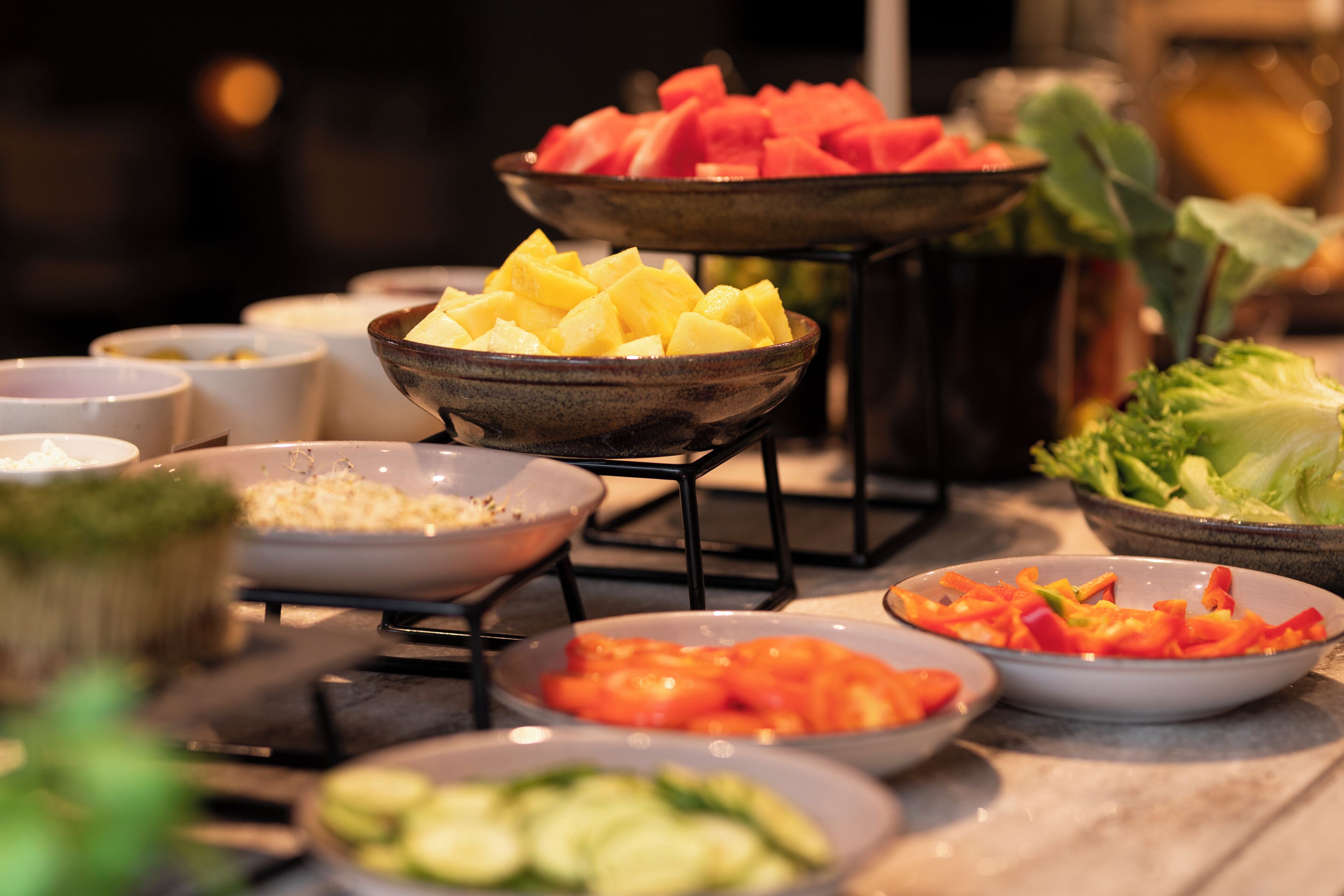 A buffet table with various food items including watermelon, pineapple, and vegetables.
