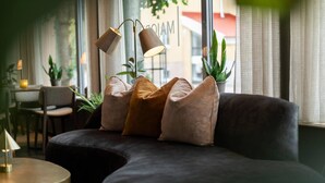 A modern living room with a dark sofa, multiple cushions, a round side table, and two floor lamps.