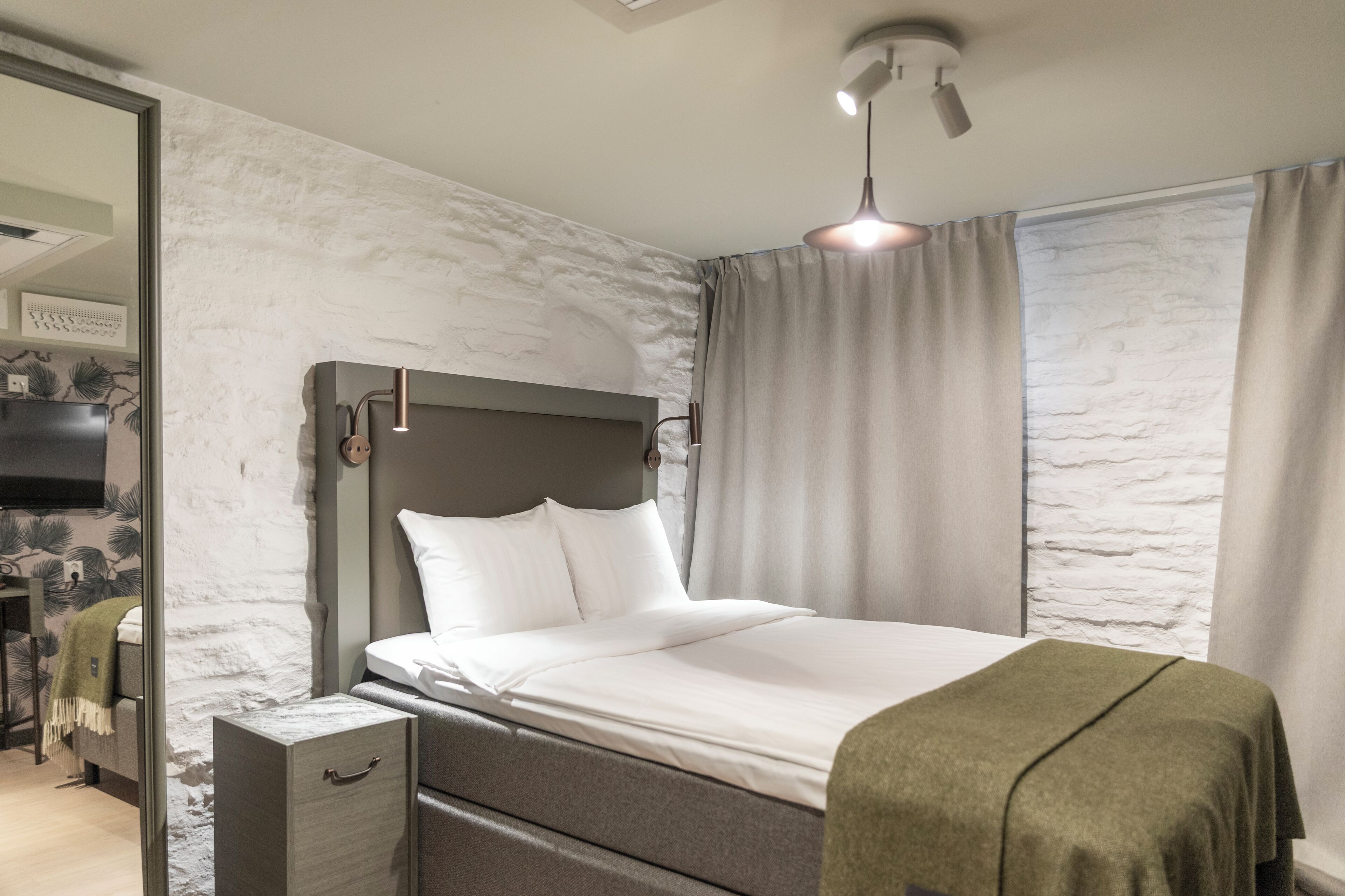 Une chambre moderne avec un lit, des tables de chevet, une armoire et une grande fenêtre avec des rideaux.