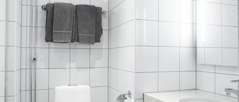 Un baño moderno con azulejos blancos, un inodoro, un lavamanos y dos toallas colgadas en un perchero.