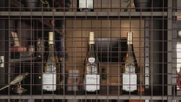 A wine rack with bottles of wine behind a metal grid.