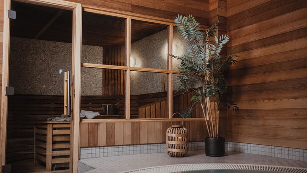 A wooden spa room with a hot tub, a wooden bench, and a potted plant. - Home Hotel Kompaniet (Nykoping)
