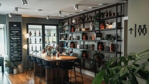 A modern bar area with a wooden bar counter, black bar stools, and shelves with various bottles and decorative items. - Home Hotel Kompaniet (Nykoping)