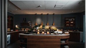 A modern kitchen with a central island, pendant lighting, and built-in shelves. - Home Hotel Kompaniet (Nykoping)