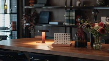 A wooden table with a modern lamp, a decorative board, and a vase with flowers.