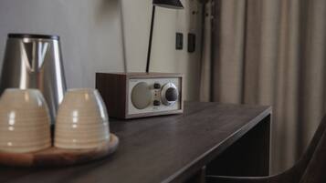 Uma mesa de madeira com um rádio, duas chávenas e um candeeiro.