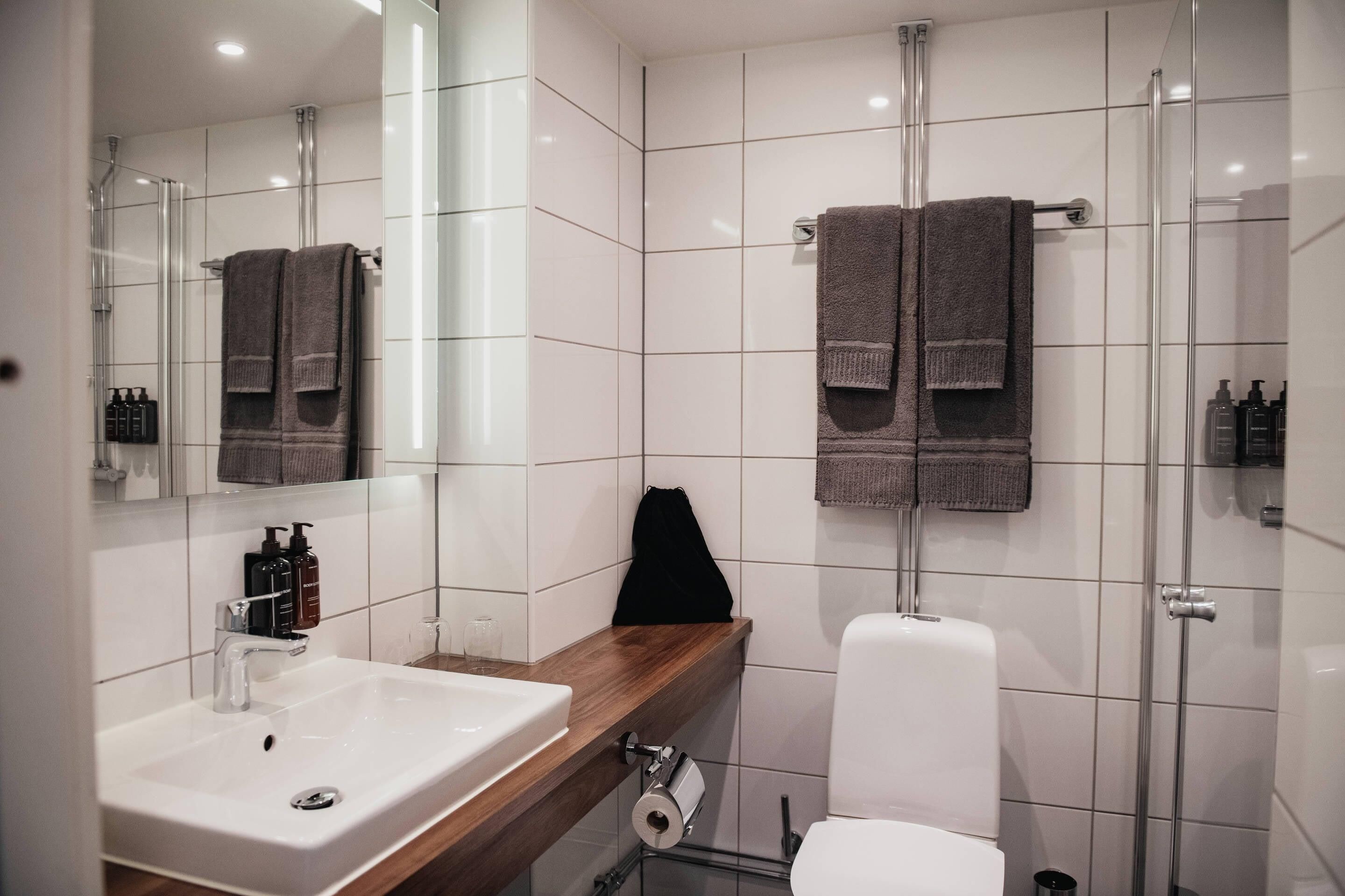 A modern bathroom with a white sink, mirror, and glass shower enclosure.