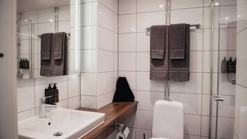 A modern bathroom with a white sink, mirror, and glass shower enclosure.
