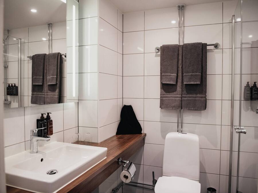 A modern bathroom with a white sink, mirror, and glass shower enclosure.