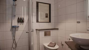 Un baño moderno con cabina de ducha de vidrio, un inodoro, un lavabo y un certificado enmarcado en la pared.