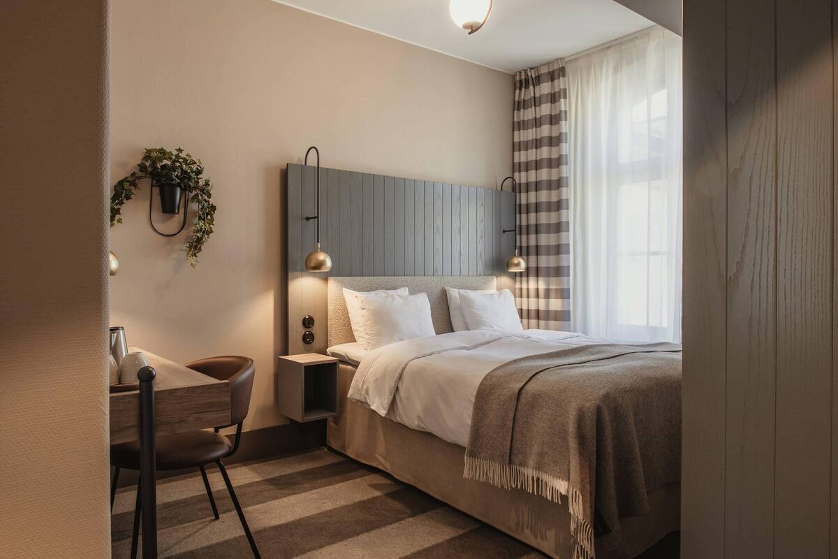 Un dormitorio moderno con cama, mesitas de noche, un escritorio y una silla.