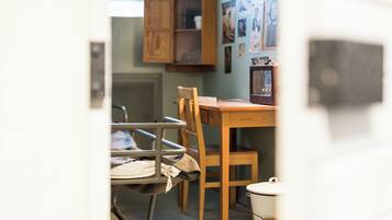 A room with a wooden dining table, a chair, a cabinet, and a radiator.