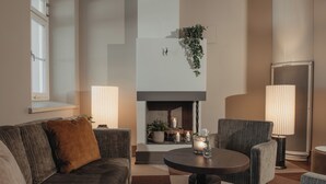 Una sala de estar moderna con un sofá, sillones, una mesa redonda, una chimenea y un ventanal grande.