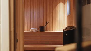 A wooden sauna with benches, a towel, and a bucket.