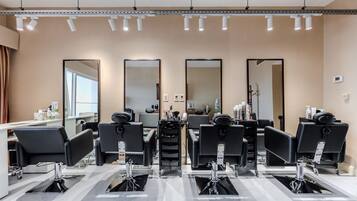 Un moderno salón de belleza con varias estaciones, cada una equipada con una silla, espejo y herramientas de peluquería.