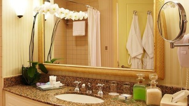A bathroom with a granite countertop, a sink, a mirror, and a potted orchid. - Enjoy Punta del Este (Punta del Este)