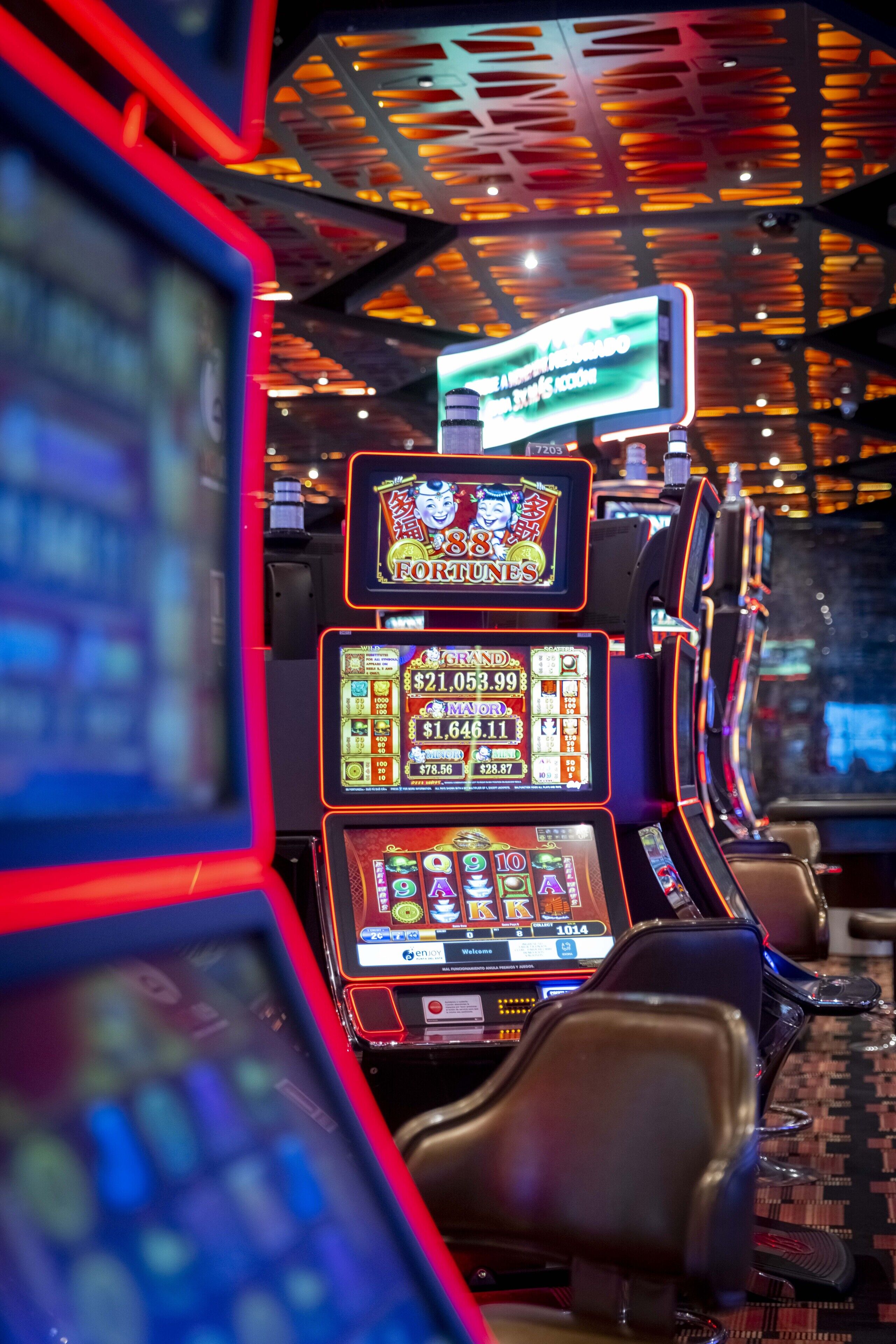 A row of slot machines with digital displays and illuminated reels.
