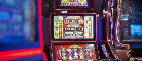 A row of slot machines with digital displays and illuminated reels.