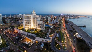 A coastal cityscape with modern high-rise buildings, a marina, and a well-lit beachfront area. - Enjoy Punta del Este (Punta del Este)