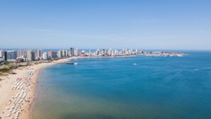 A coastal cityscape with a wide beach, numerous high-rise buildings, and a clear blue sea. - Enjoy Punta del Este (Punta del Este)