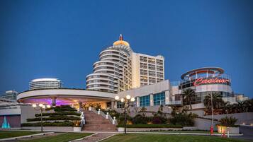 Un hotel con una fachada curva distintiva, un llamativo letrero de casino y una escalera central que conduce a la entrada.