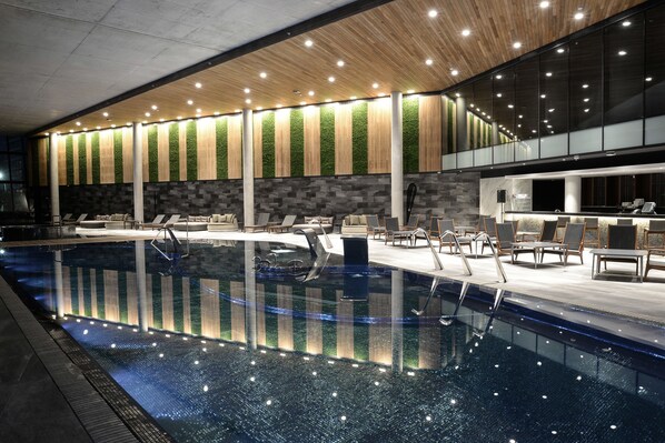 Una piscina techada, una piscina al aire libre de temporada, sombrillas