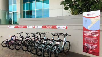 Varias bicicletas estacionadas junto a una pared, con un anuncio de un servicio de alquiler de bicicletas.