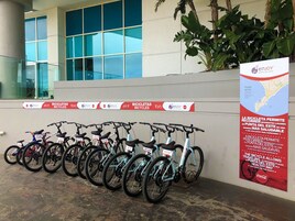 Varias bicicletas estacionadas junto a una pared, con un anuncio de un servicio de alquiler de bicicletas.