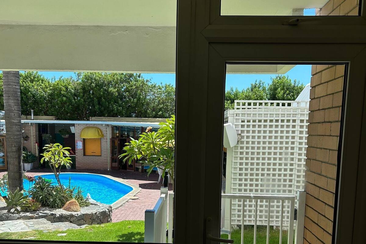 Blick von einem Balkon mit Pool, weißem Stuhl und weißem Zaun.