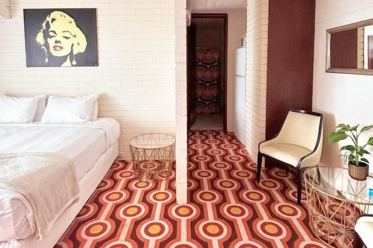 Ein Hotelzimmer mit einem Bett, einem Sessel, einem kleinen Tisch und einem gemusterten Boden.