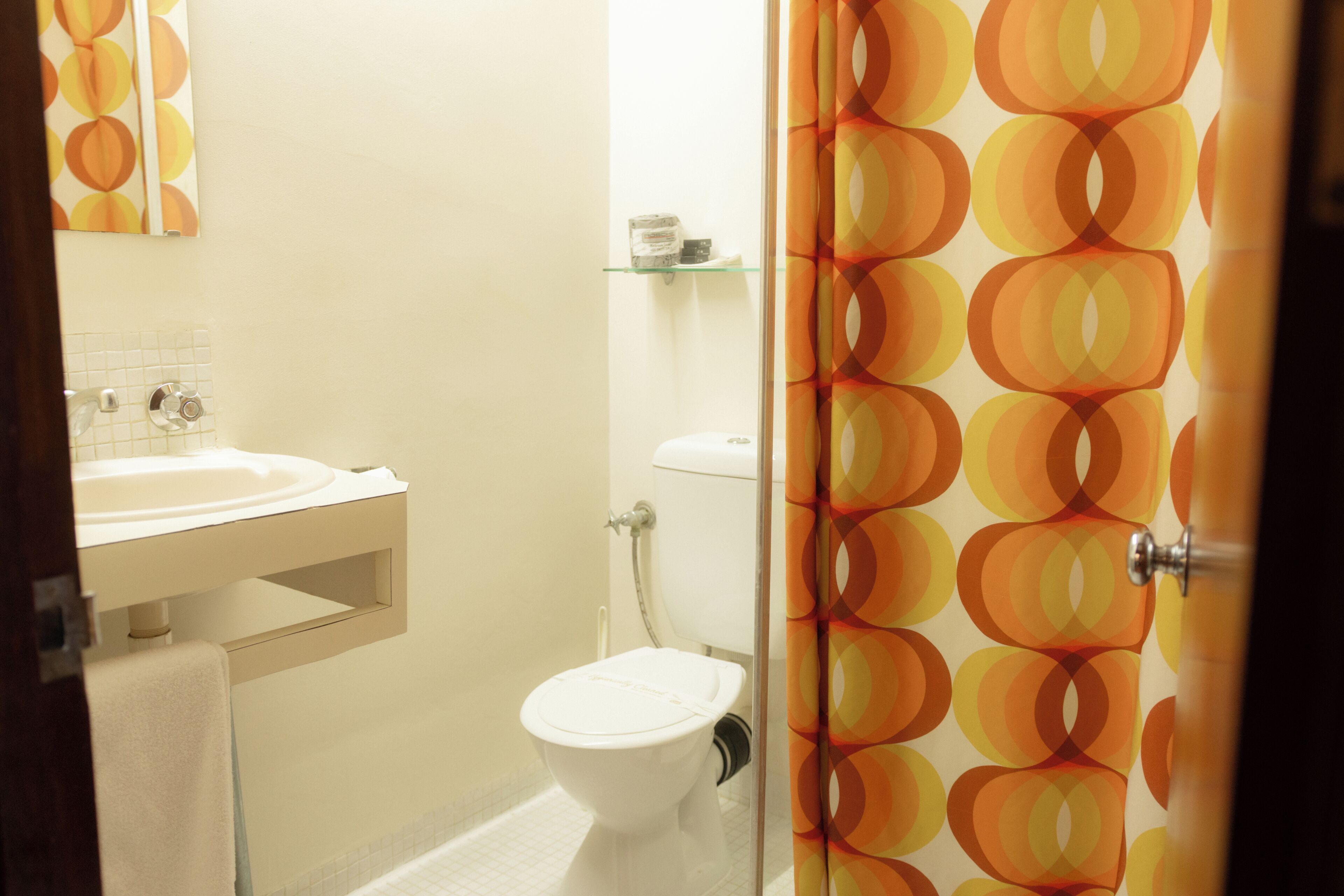 Un baño con inodoro, lavabo y estante de vidrio.