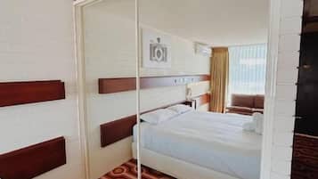 Habitación de hotel con cama, espejo, alfombra estampada y cámara de seguridad en la pared.