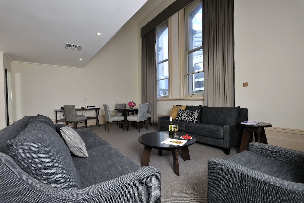 A modern living room with grey sofas, a round coffee table, and a dining area with a table and chairs.