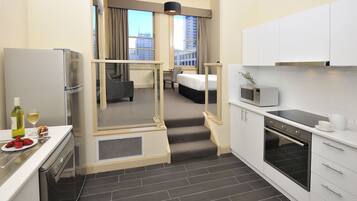 Una habitación de hotel compacta con kitchenette, una cama con vistas y un pequeño comedor.