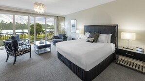 A spacious hotel room with a large bed, a balcony with a view of the lake, and a seating area with a table and chairs. - The Carrington Hotel Shepparton (Shepparton)